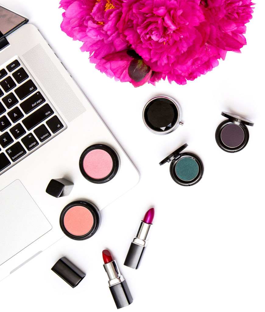 Makeup sitting by a laptop with fuchsia colored flowers for virtual makeup lessons